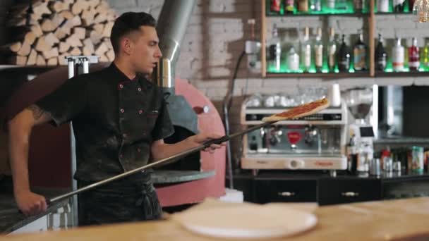 Шеф-повар достает из плиты запеченную пиццу — стоковое видео