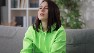 Yorgun kadın koltukta otururken kafasına dokunuyor.