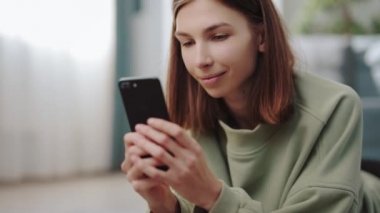 Evde akıllı telefon kullanan bir kadın.