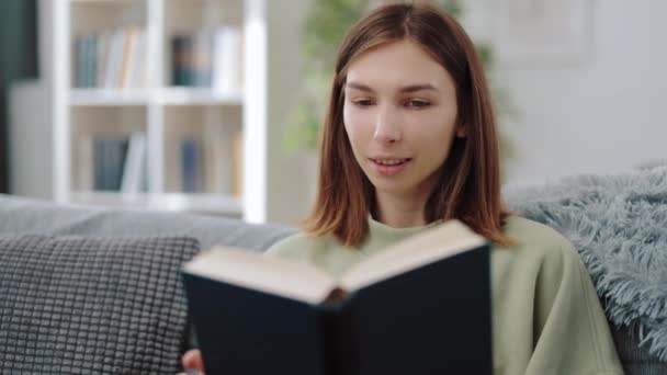 Mujer emocionada leyendo libro en casa — Vídeo de stock