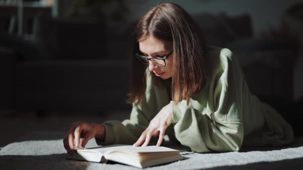 Vrouw liggend op de vloer en leesboek — Stockvideo