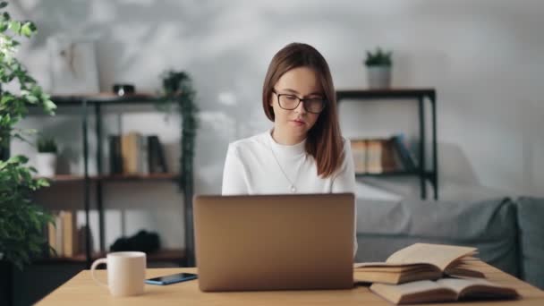 A tanuló laptopot használ és könyvet olvas otthon — Stock videók