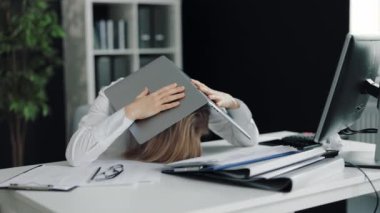 Kafasında dizüstü bilgisayarı olan depresyonda bir kadın.