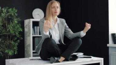 İş kadını masada meditasyon yapıyor.