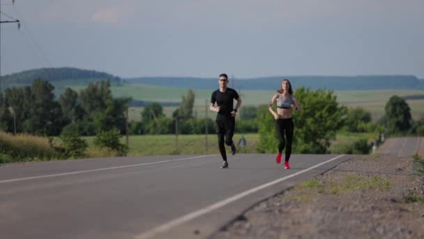 Пара бегущих по асфальтовой дороге — стоковое видео