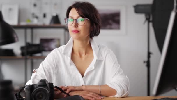 Kvinnlig fotograf sitter på kontoret — Stockvideo