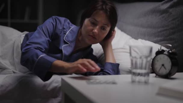 Kvinde tager piller i sengen – Stock-video