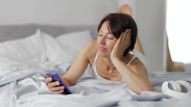 Femme utilisant un smartphone au lit — Video