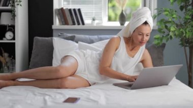 Yatakta dizüstü bilgisayar kullanan kadın