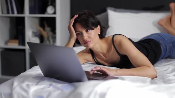 Vrouw liggend op bed met laptop — Stockvideo