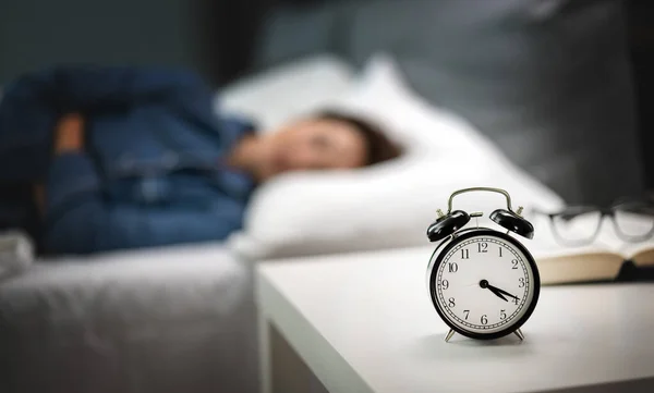 Zegar nocny w pobliżu śpiącej kobiety — Zdjęcie stockowe