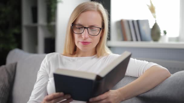 Kobieta czyta książkę na kanapie — Wideo stockowe