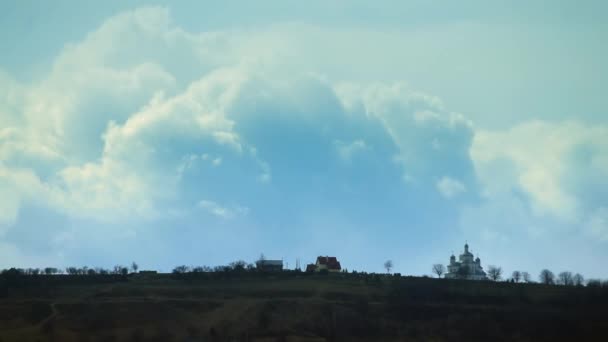 Pueblo de montaña con la iglesia sobre un fondo de nubes blancas — Vídeos de Stock