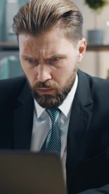 Bir iş adamı modern bir ofiste dizüstü bilgisayarda dikkatle çalışır. Konsantrasyonu yoğun bir iş günü boyunca görevlere adanmış bir yaklaşımı yansıtır. Çevre profesyonel ve düzenli..