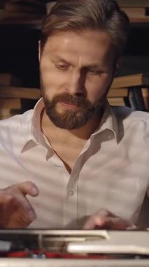 Bir adam, kendi çalışma odasında daktiloyla yazı yazarak daktilo yazar. Sıcak ışık yaratıcı bir atmosfer yaratıyor..