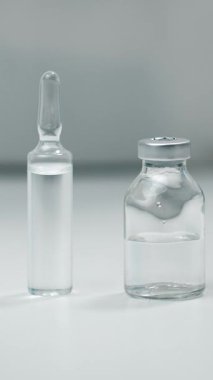 Bir doktor steril eldiven ve şişelerle klinik ortamda aşı hazırlıyor. Yönetimden önce güvenlik ve hijyen sağlanıyor..