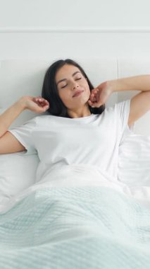 Yeni bir günün ferahlatıcı başlangıcını hisset. Bir insan uyanır, uzanıp, yatakta sükûnet anının tadını çıkarır..