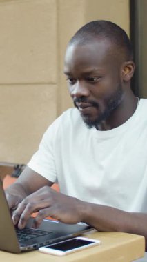 Siyah bir laptopçu kafede dizüstü bilgisayarında yazan bir adam gün geçtikçe işine odaklanıyor..