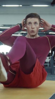 Bir adam modern bir spor salonunda karın kasları egzersizi yapar. Çekirdek kuvveti ve zindeliğine odaklanır..