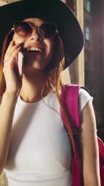 Bir turist telefonda konuşurken güneşli bir günün tadını çıkarır, şehir hayatını gözler önüne serer ve seyahat neşesini.