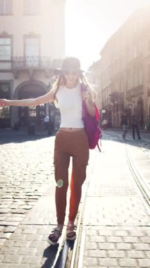 Bir turist büyüleyici bir cadde boyunca geziyor, rahat bir moda sergilerken güneşin ve atmosferin tadını çıkarıyor..