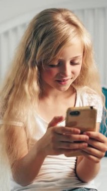 Genç kız kapalı bir ortamda akıllı telefonuyla mesajlaşırken gülümsüyor, eğlenceli ve eğlenceli bir hava yaratıyor..