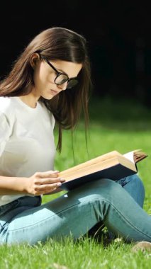 Bir öğrenci gün batımında çimlerde kitap okurken sakin bir anın tadını çıkarır.