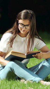 Öğrenci, sıcak bahar güneşinin altındaki bir kitaba daldırılmış çimlerde dinleniyor ve huzurlu bir çalışma anını yakalıyor.