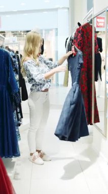 Şık bir elbise satışını keşfetmek için alışverişçilerin canlı bir mağazada ideal kıyafeti aradığı bir yer.