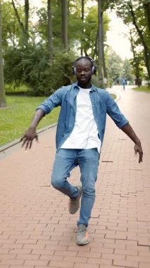 Parkta neşeyle dans eden bir adam özgürlüğünü ve mutluluğunu ifade ederken temiz havanın ve güneşin tadını çıkarıyor.