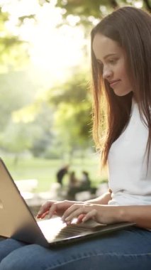 Doğayla çevrili güneşli bir parkta dizüstü bilgisayarında bu huzurlu anın tadını çıkarın.