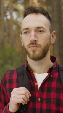 Ağaçlar ve doğa ile çevrili, huzurlu atmosferin tadını çıkaran bir adam ormanda duruyor..