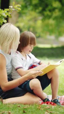 Parkta bir çocuk, renkli sanatlar yaratmaya çalışan bir bakıcıyla oturuyor.