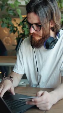 Kafedeki adam rahat bir ortamın tadını çıkarırken kart ödemesini yapmak için dizüstü bilgisayar kullanıyor.