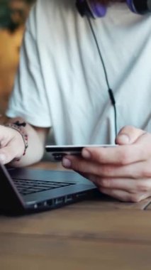 Müşteri, gün boyunca rahat bir kafede dizüstü bilgisayar kullanırken kart ödemesi yapıyor.