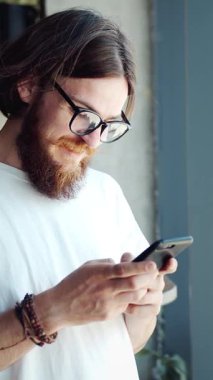 Bir adam bir kafede oturur ve öğleden sonraları akıllı telefonuyla mesaj atmaya odaklanır.