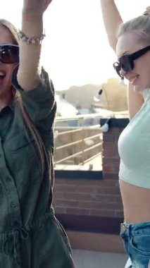 Dostlar neşeli bir parti sırasında çatıda gülüp dans ederek kutlama yaparlar.