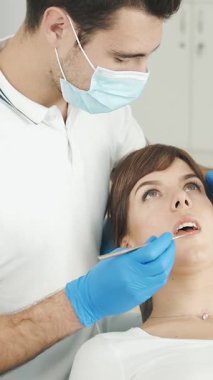 Bir kadın parlak ofisteki uzman bir asistandan diş tedavisi görür.