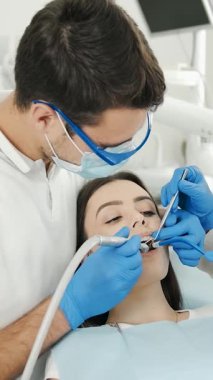 Diş cerrahisi uzman bir asistanın hastaya yardım ettiğini gösteriyor.