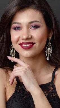 Bir stüdyo ortamında güzel ışıklandırmayla gülümserken kadın makyaj ve saç stillerini gösterir.