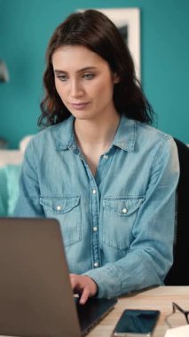 Bir kadın ev ortamında çalışırken dizüstü bilgisayarına odaklanır.