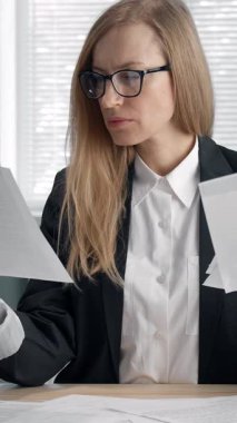 Bir iş kadını masadaki önemli evraklara bakar içeriği kafasını karıştırmış gibi görünür.