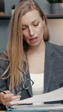 İş kadını, ofiste belgeleri incelerken görüntülü konuşma sırasında konuşuyor