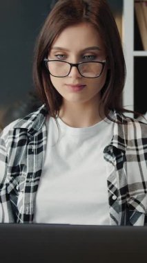 Kadın ev ofisinde çalışırken dizüstü bilgisayara odaklanıyor..