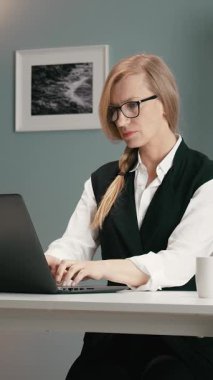 Bir kadın masasında dizüstü bilgisayar kullanırken işine odaklanır..