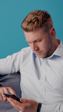 Adam koltukta otururken akıllı telefona bakıyor..