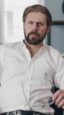 Bir adam arama sırasında dizüstü bilgisayarın önünde oturur ve gözlüklerini ayarlar..