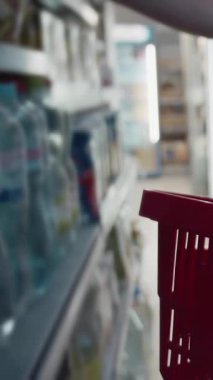 Bir kadın, parlak bir markette raflardan pek çok ürünle birlikte eşyalar alır..