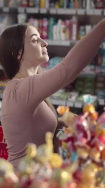 Kadın farklı seçenekleri incelerken bir mağazadan abur cubur seçiyor..