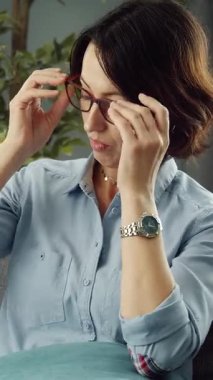 Bir kadın gözlerini ovuşturur ve rahat bir evdeki kanepede dinlenirken biraz zaman geçirir..